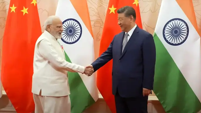 ভারতের প্রধানমন্ত্রী নরেন্দ্র মোদি এবং চীনের প্রেসিডেন্ট শি জিনপিং হাত মেল্লাচ্ছেন এবং পিছনে দুই দেশের পতাকা দেখা যাচ্ছে।