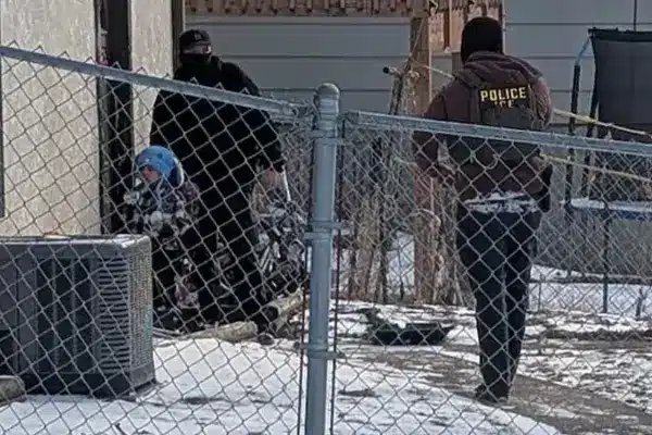 মুখোশ পরিহিত ইমিগ্রেশন পুলিশের সদস্যরা শিশুটির পাশে দাঁড়িয়ে আছেন।