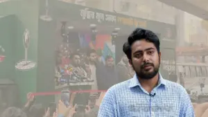 এনসিপির প্রার্থী নাহিদ ইসলাম এবং পেছনে তার নির্বাচনী প্রচারের বিলবোর্ড।