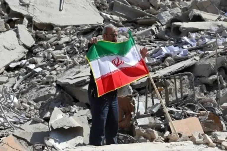 ধ্বংসস্তূপে ইরানের পতাকা হাতে এক ব্যক্তি।