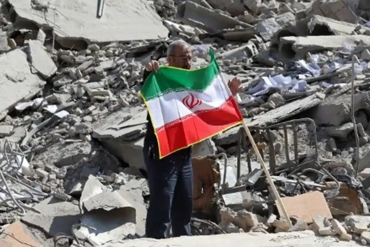 ধ্বংসস্তূপে ইরানের পতাকা হাতে এক ব্যক্তি।